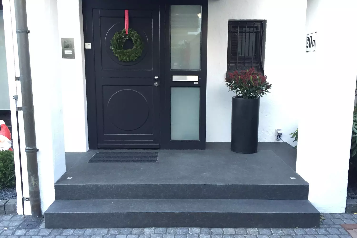 Individueller Hauseingang mit passgenauen Natursteinstufen in elegantem Dunkelgrau.