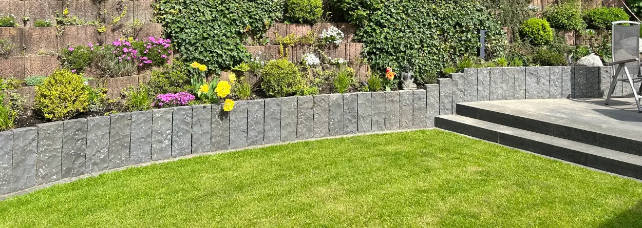 Garten mit Rasenfläche, Sichtschutzmauer aus Naturstein und Basalt-Treppenstufen