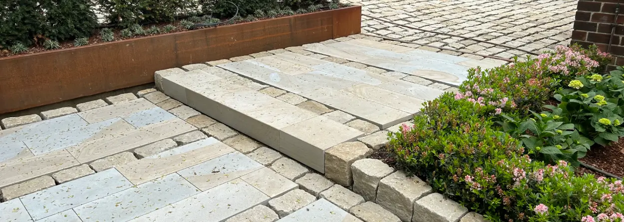 Gartenweg aus hellen Ruhrsandsteinplatten mit Blockstufe, Pflastersteinen und seitlicher Beetbepflanzung