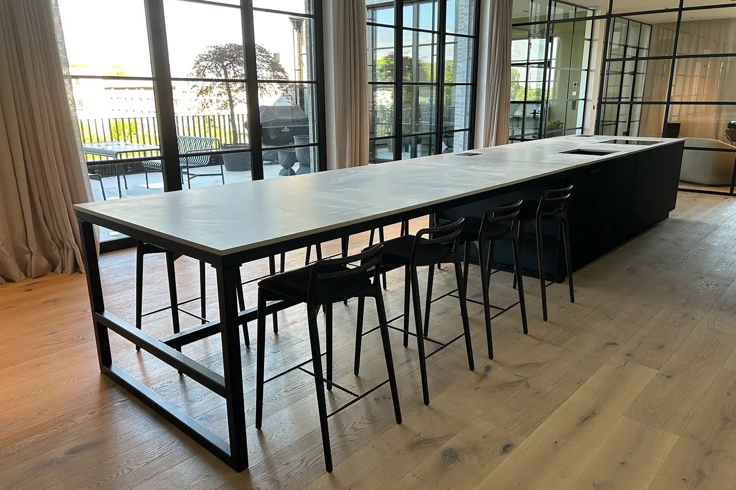 Küche mit heller Naturstein-Arbeitsplatte und langem Esstresen in modernem Loft mit großen Fensterfronten
