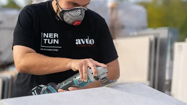 Mitarbeiter von avdo design schleift eine Natursteinplatte mit einem Winkelschleifer