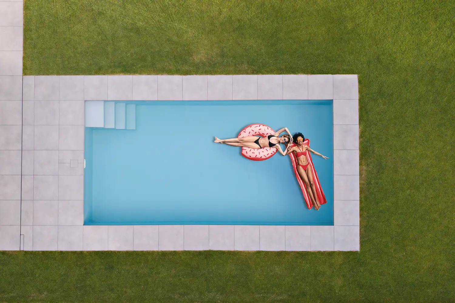 Moderne Poolanlage mit Poolumrandung aus Keramikplatten und gepflegter Rasenfläche