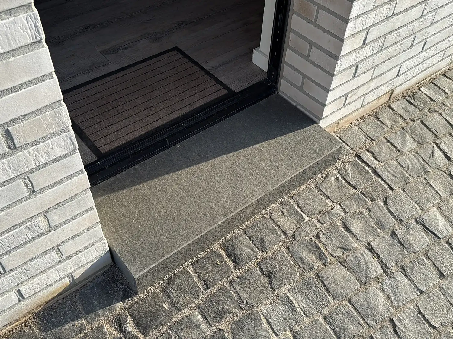 Pflastersteine Naturstein Granit am Hauseingang mit passender Naturstein-Stufe