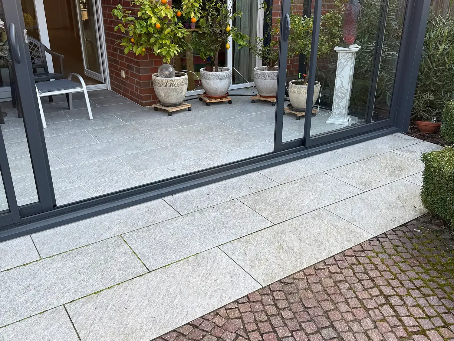 Pflastersteine Naturstein im Segmentbogen vor Terrasse mit großformatigen Terrassenplatten