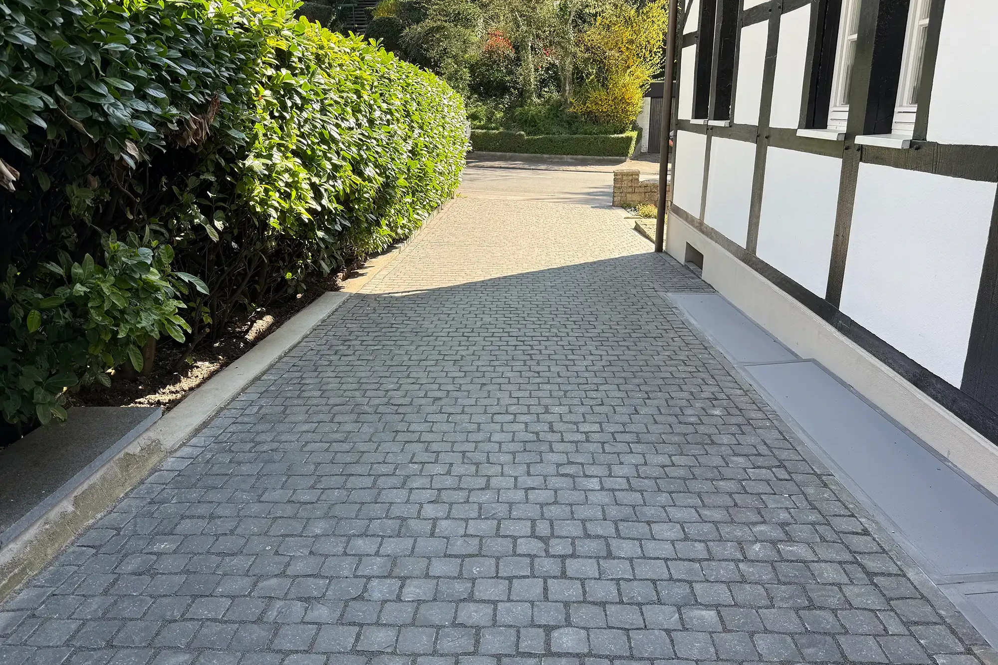 Pflastersteine aus Naturstein Basalt Kleinpflaster in Hofzufahrt neben Fachwerkhaus