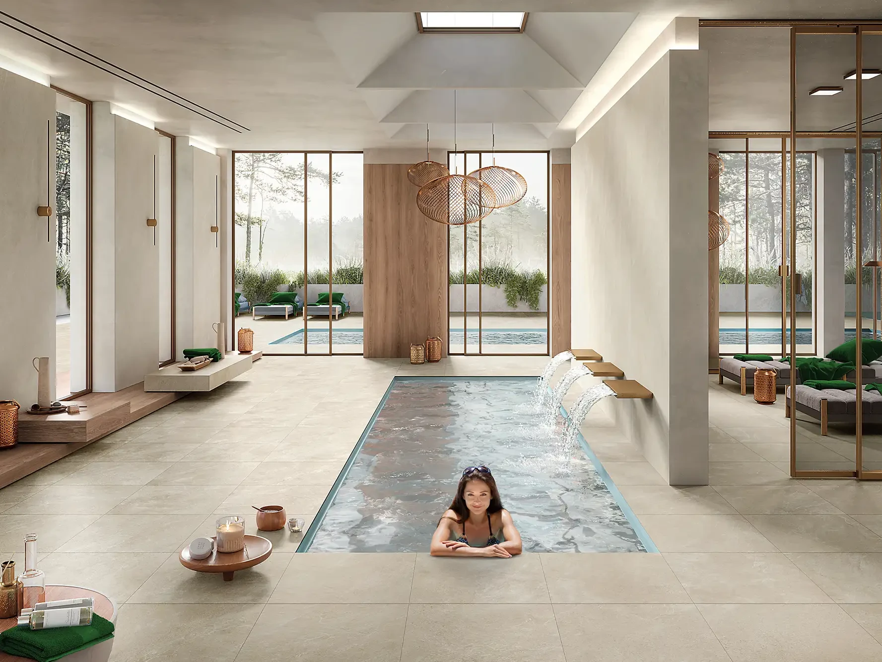 Frau in eingelassenem Indoor-Pool eines Wellness-Spas mit cremefarbenen Großformat-Keramikfliesen, Wasserfall-Feature und Blick auf Außenpool