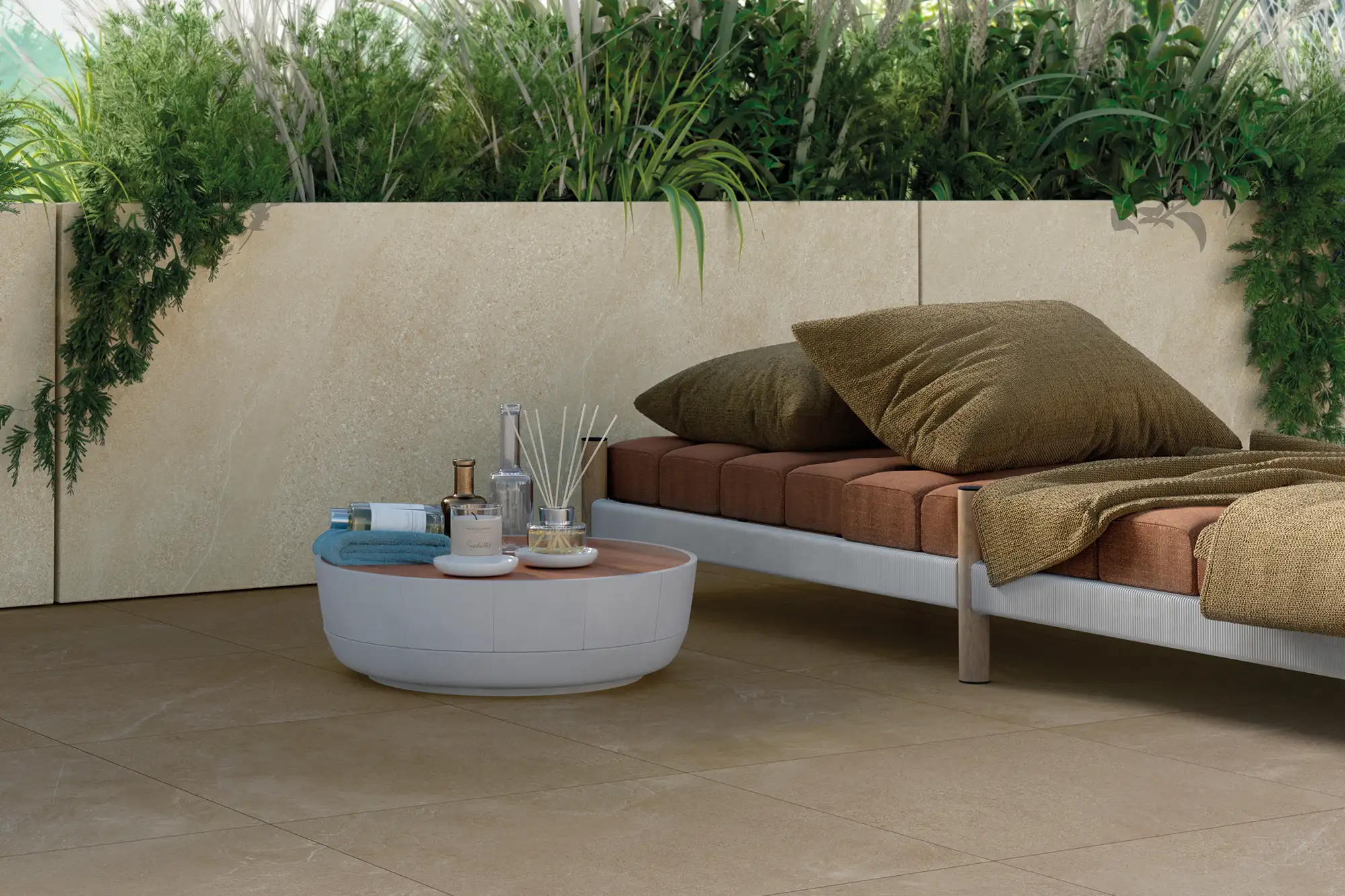 Entspannte Outdoor-Lounge mit großformatigen Keramikplatten in Sandsteinoptik als Bodenbelag und Wandverkleidung, Liegesofa mit Erdtönen und üppiger Bepflanzung