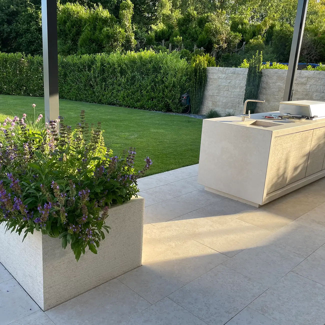 Terrasse mit Bodenplatten aus Naturstein im Garten mit Outdoor-K&uuml;che
