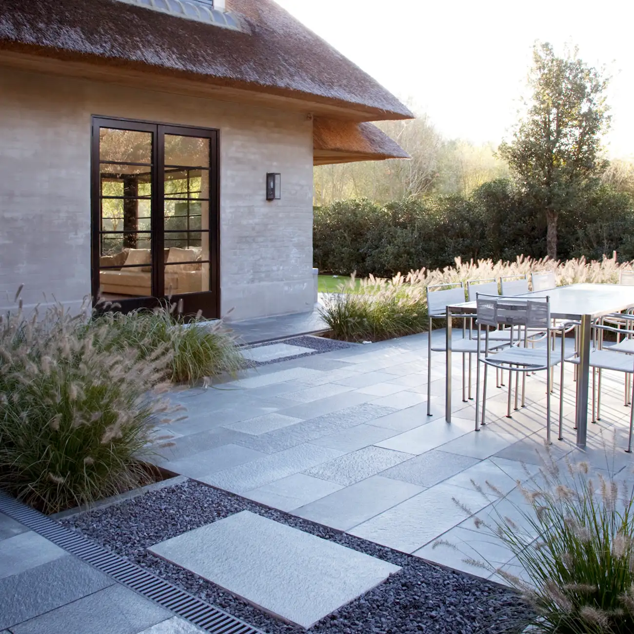 Terrasse mit Bodenplatten aus Naturstein im Garten am Haus