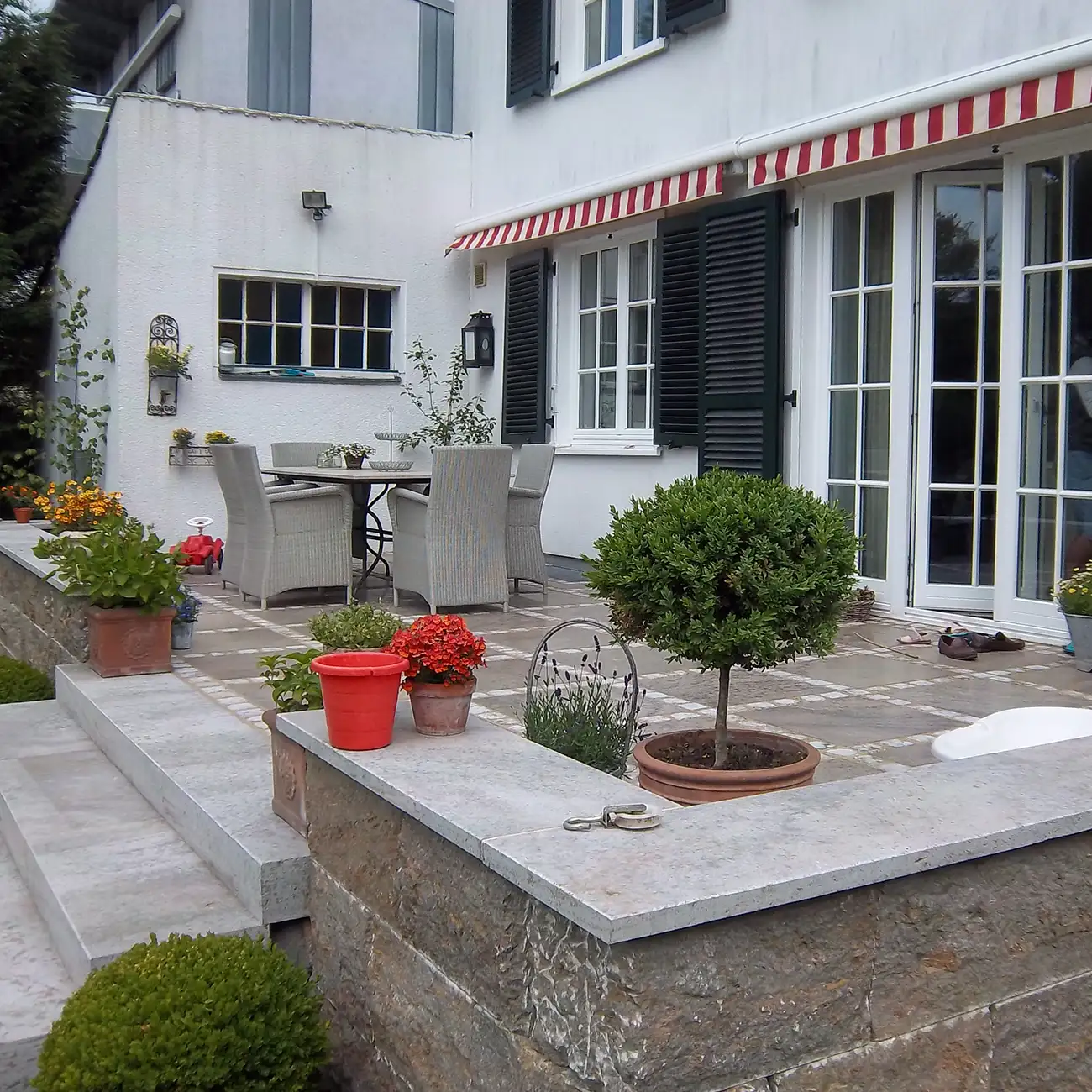 Terrasse mit Bodenplatten aus Naturstein vor Wohnhaus