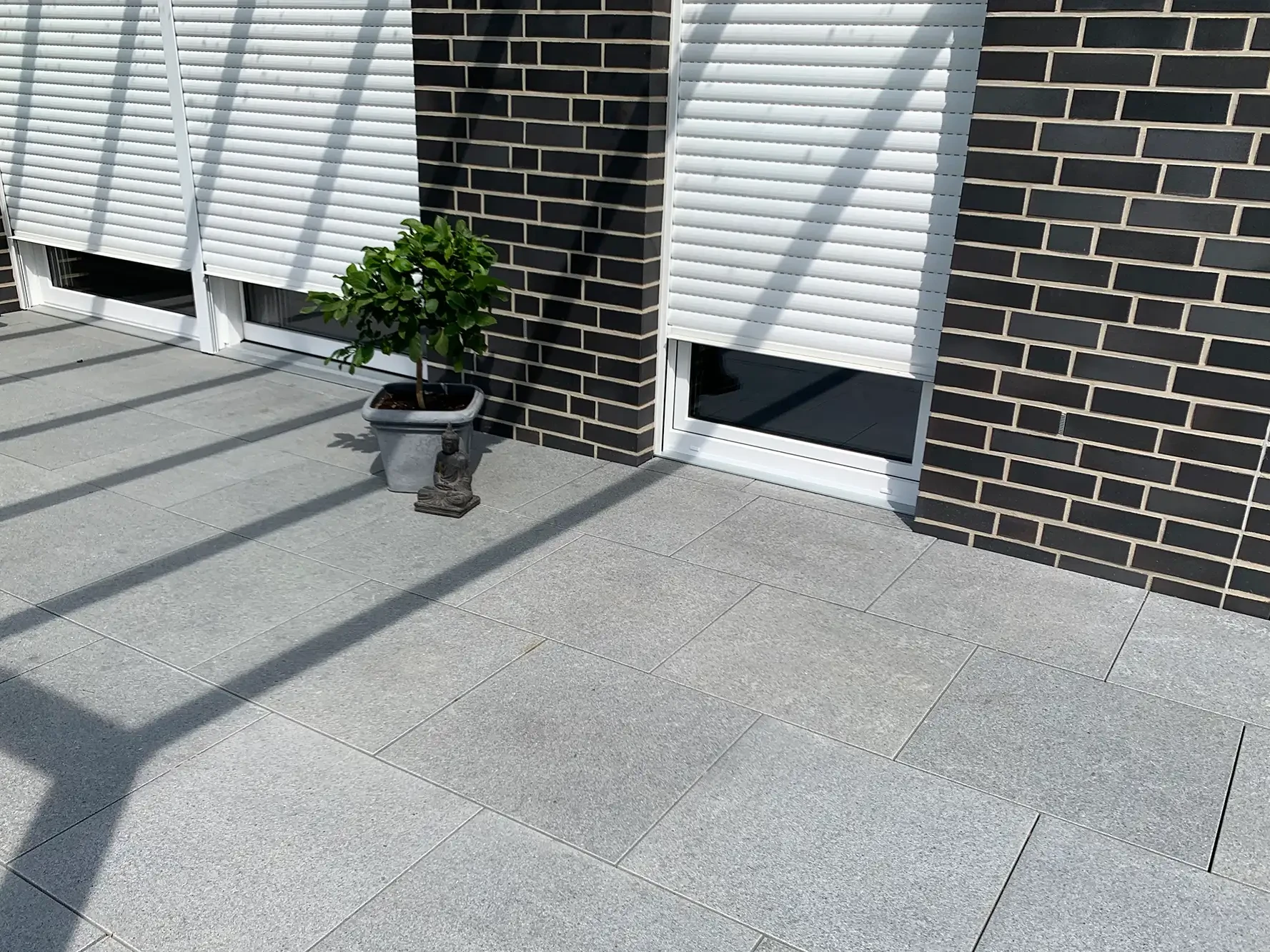Terrasse mit Bodenplatten aus Naturstein im Außenbereich am Haus