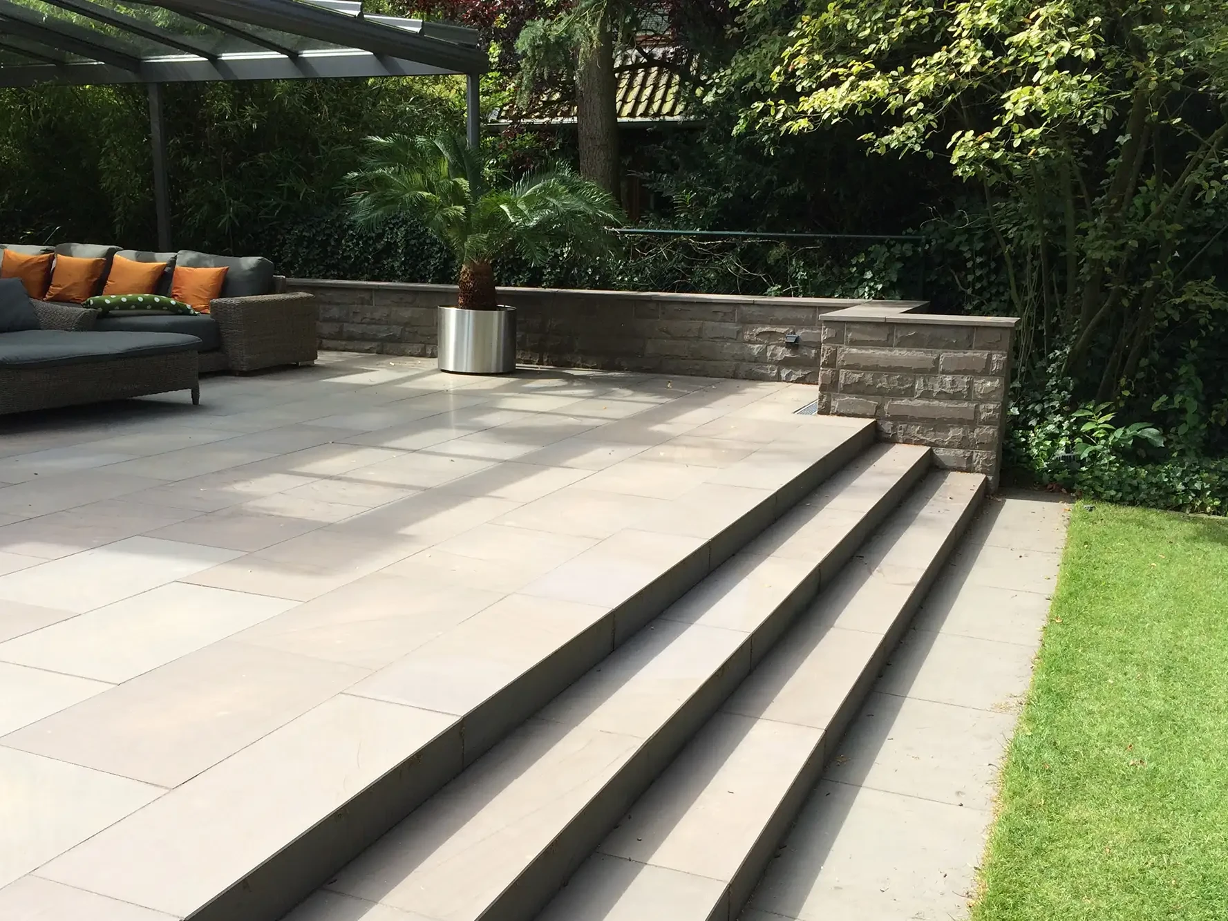Terrasse mit Bodenplatten aus Naturstein und Treppenstufen im Garten