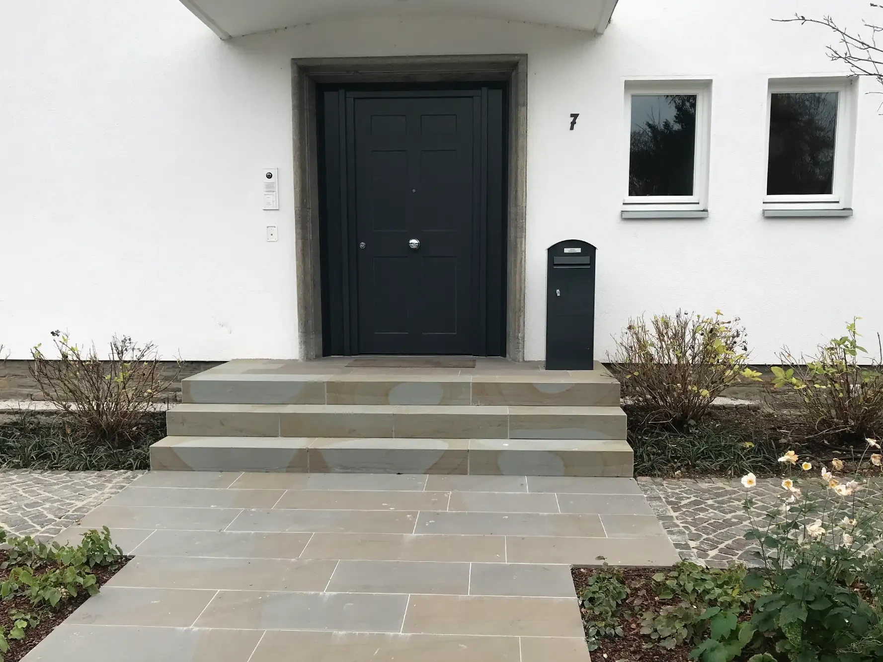 Hauseingang mit Bodenplatten aus Naturstein und Naturstein-Treppenstufen