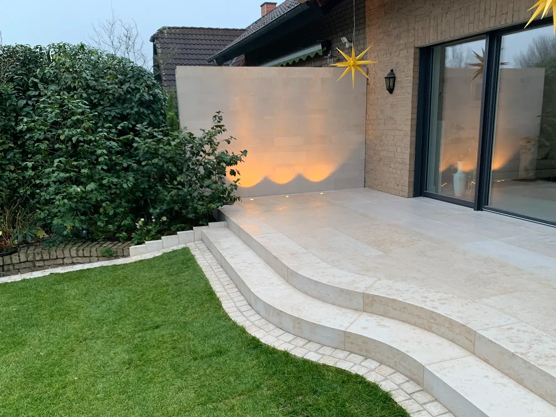 Terrasse mit Bodenplatten aus Naturstein und geschwungenen Naturstein Treppenstufen im Garten
