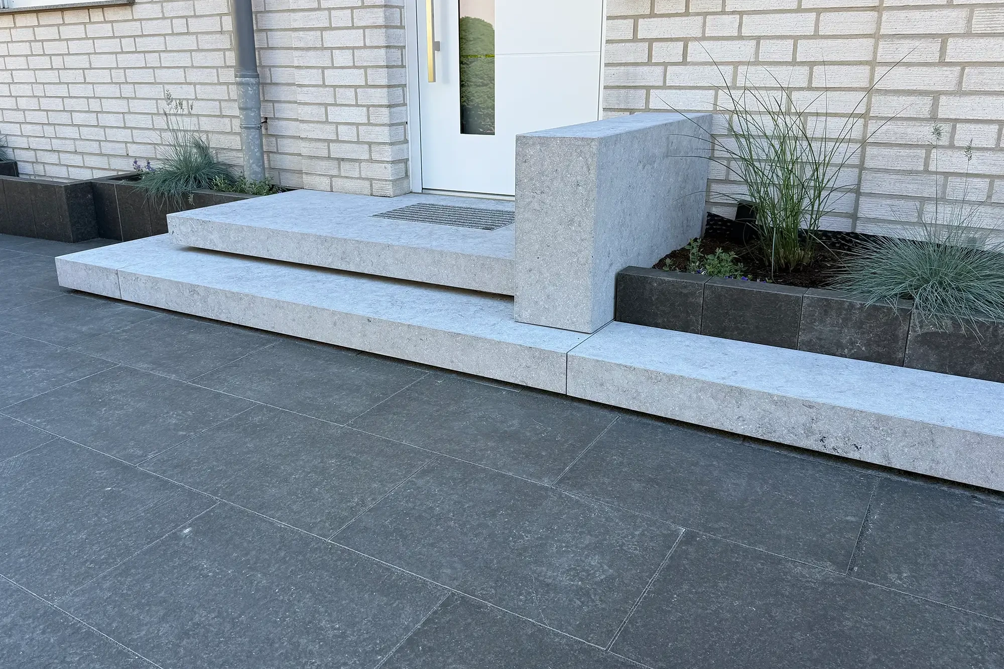 Terrasse mit Bodenplatten aus Basalt Black Aviator Naturstein und Natursteinstufen am Hauseingang