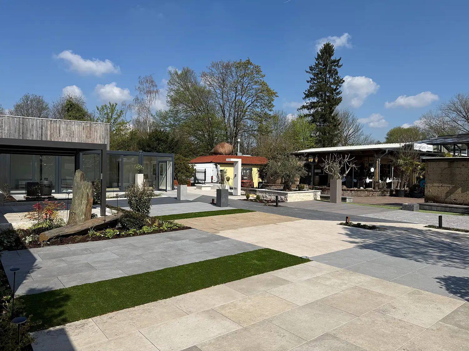 Panoramablick auf die Gartenausstellung avdo design in Mülheim an der Ruhr mit Keramikplatten-Flächen, Hochbeeten, Monolithen und Glaspavillon