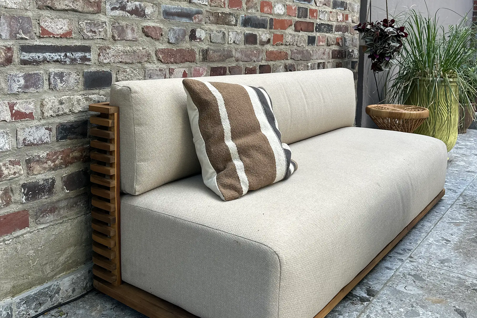 Terrassen-Lounge mit Outdoor-Sofa, grauen Steinplatten, Klinkerwand und stilvoller Bepflanzung
