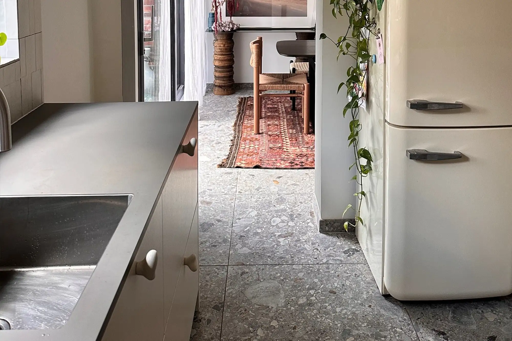 Moderne Küche mit grauem Steinboden, Spüle, Retro-Kühlschrank und offenem Übergang zum Wohnbereich