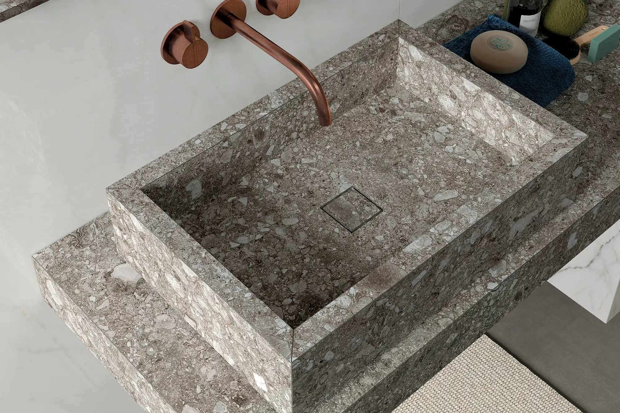 Detailansicht eines modernen Waschtischs in Terrazzo-Optik mit integriertem Becken, Kupferarmatur und hochwertiger Steinoberfläche