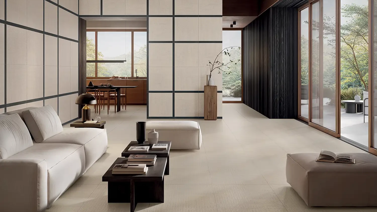 Heller Wohnraum mit cremefarbenen Keramikplatten in Unifarben-Optik, modularem Sofa und Rasterfenstern.
