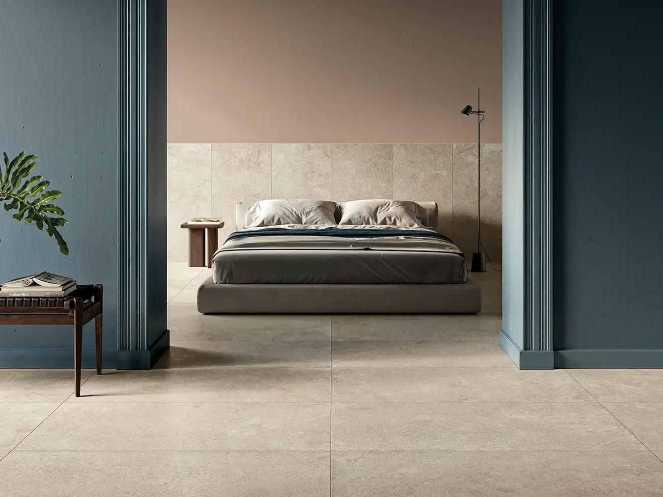 Schlafzimmer mit sandbeigen Keramikplatten am Boden, Doppelbett sowie blau und altrosa gestrichenen Wänden.