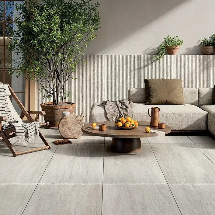 Mediterrane Terrasse mit hellgrauen Keramikplatten in Steinoptik, Holzliegestuhl, Loungesofa und Olivenbaum.