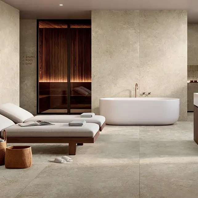 Modernes Spa-Bad mit beigen Keramikplatten in Steinoptik, freistehender Badewanne, Sauna und Ruheliegen.