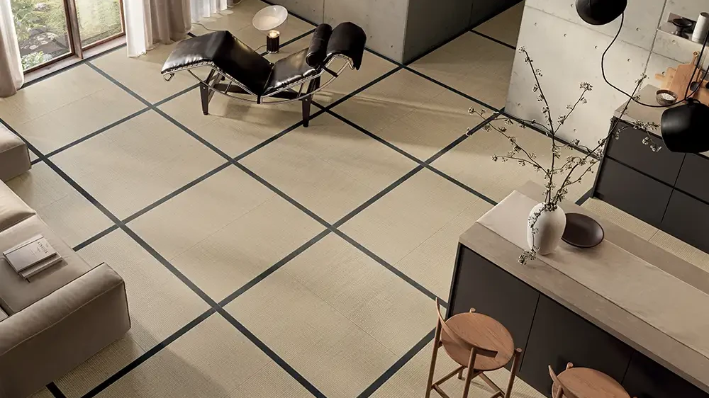 Wohnraum mit großformatigen cremefarbenen Keramikplatten, im Raster mit Fugen verlegt, Loungesessel.