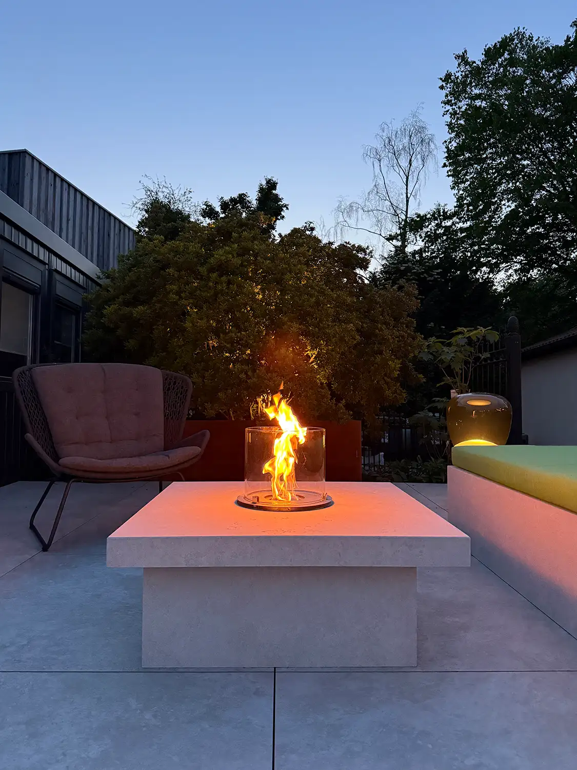 Kamintisch aus Kanfanar-Kalkstein mit Glas-Windschutz und Flamme im modernen Außenbereich.