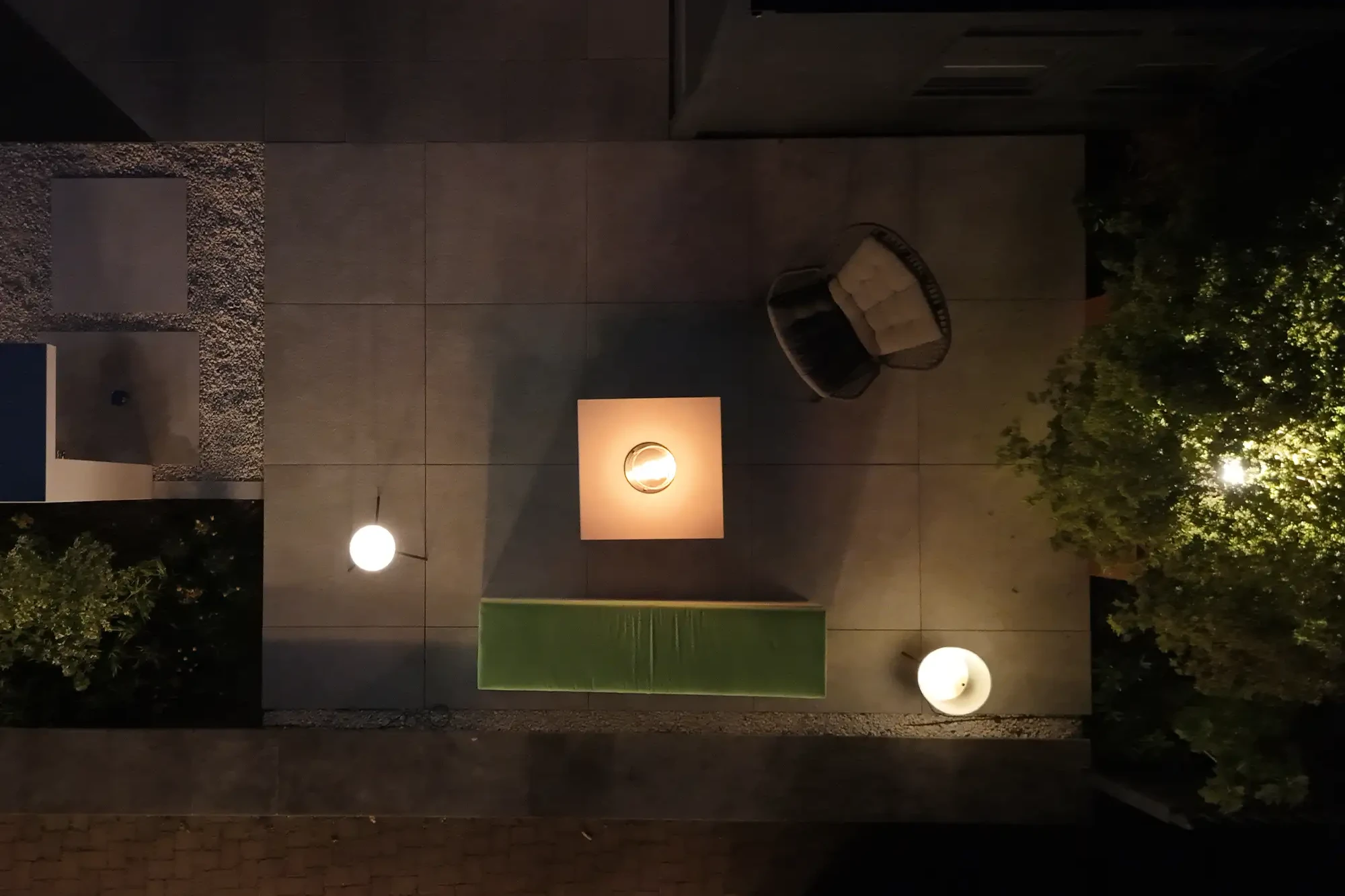 Luftaufnahme einer Terrasse mit Kamintisch, Feuerstelle, Lounge-Möbeln und Außenbeleuchtung.