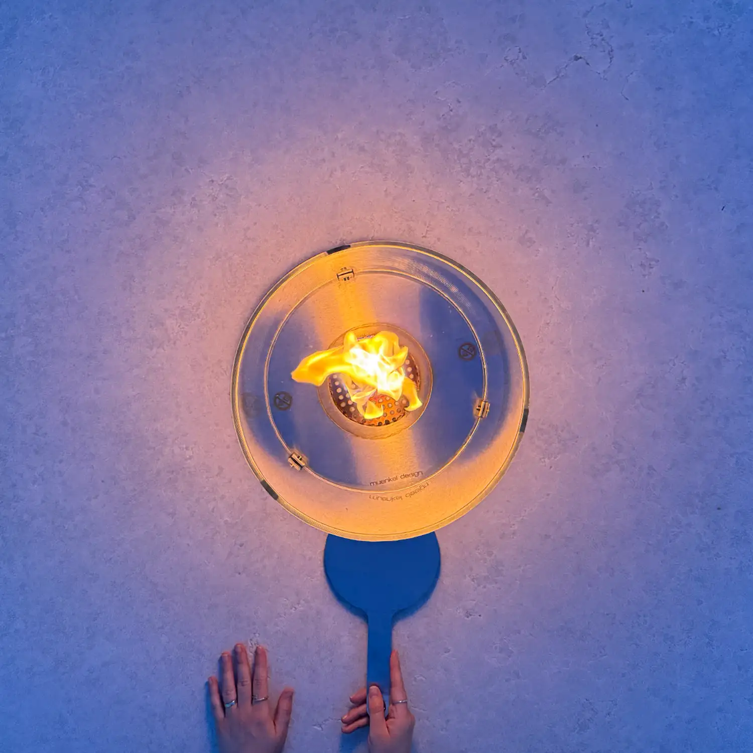 Draufsicht auf monolithischen Kamintisch aus Kanfanar-Kalkstein mit Glas-Windschutz und Flamme.