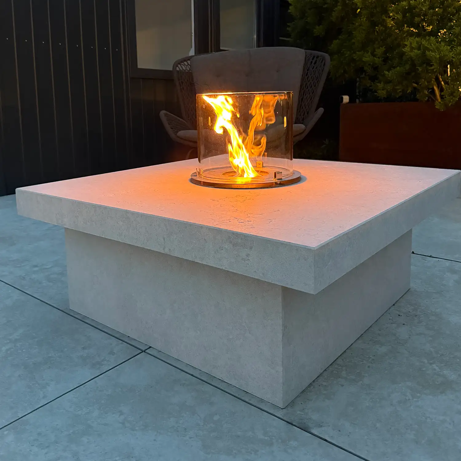 Rundes Flammenbild mit Glas-Windschutz auf Kamintisch aus Kanfanar-Kalkstein.