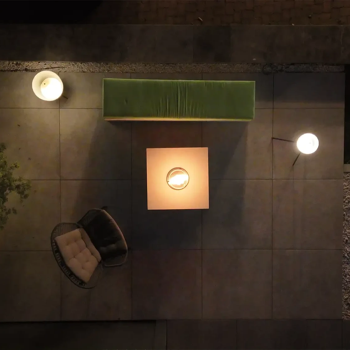 Draufsicht auf Kamintisch mit Feuerstelle, Lounge-Möbeln und Außenbeleuchtung auf moderner Terrasse.