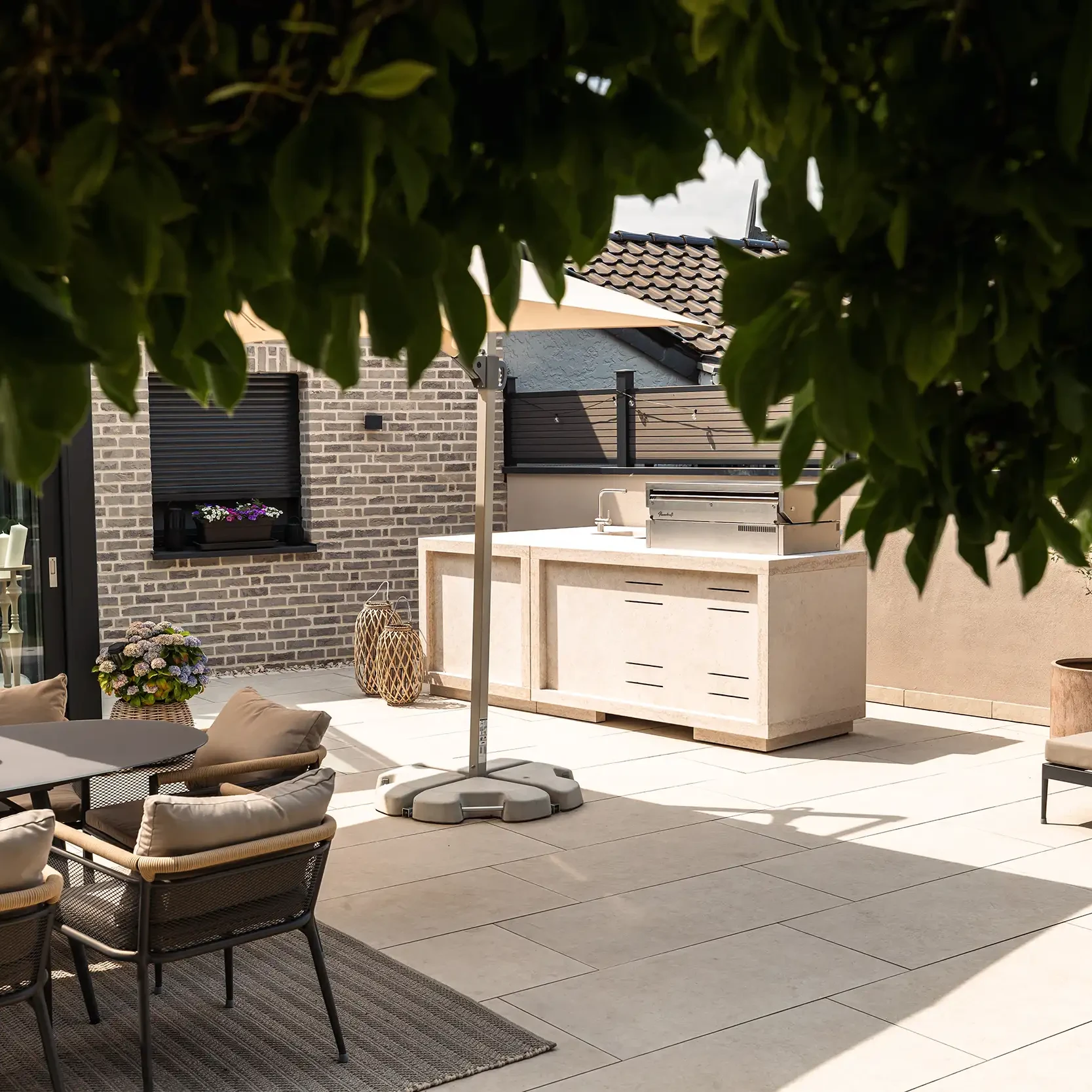 Outdoorküche aus Naturstein auf einer modernen Terrasse mit Sitzbereich und Gartenmöbeln